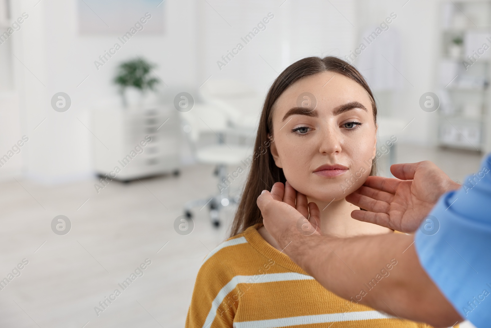 Photo of Doctor examining woman's throat in clinic during appointment