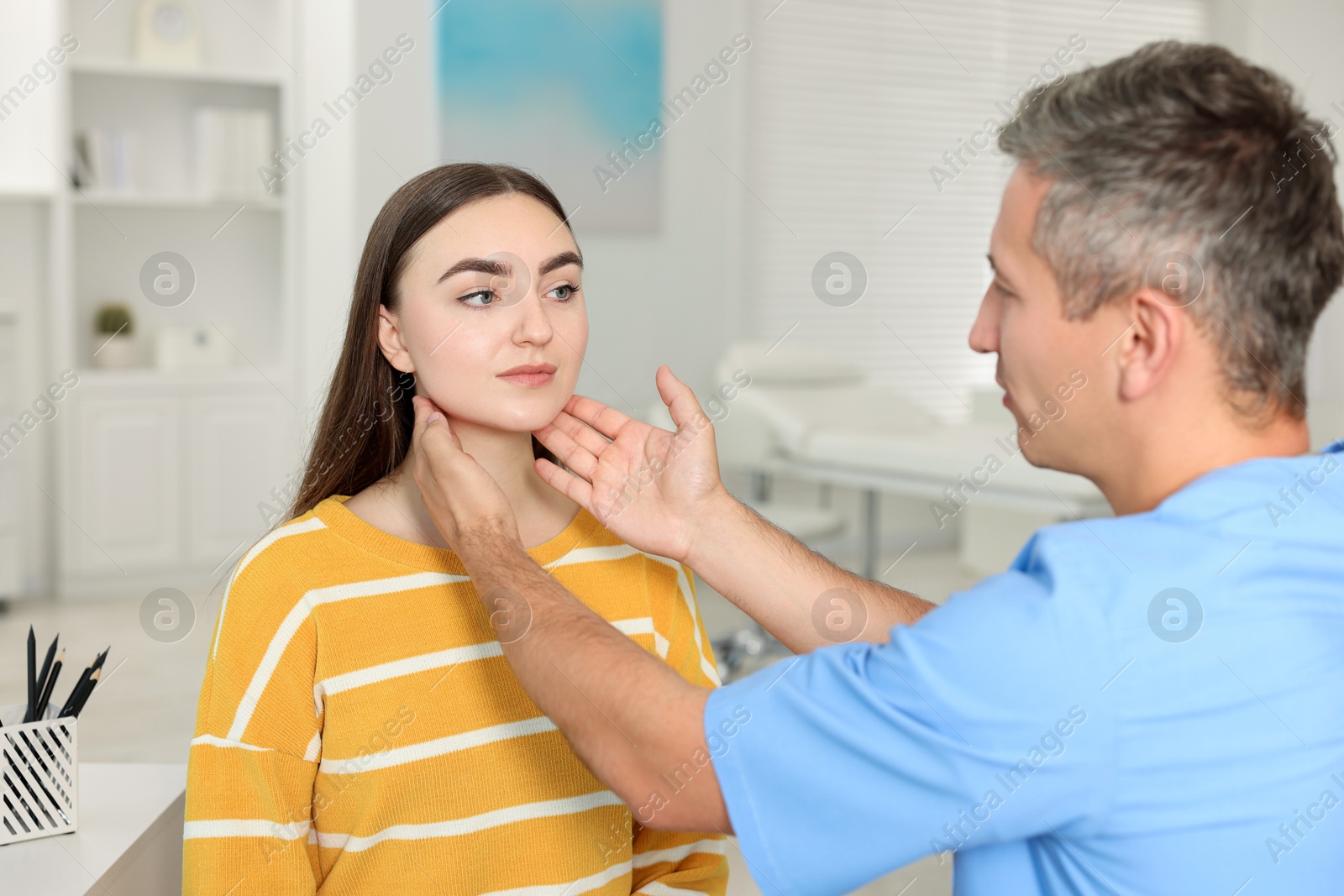 Photo of Doctor examining woman's throat in clinic during appointment