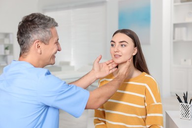 Photo of Doctor examining woman's throat in clinic during appointment