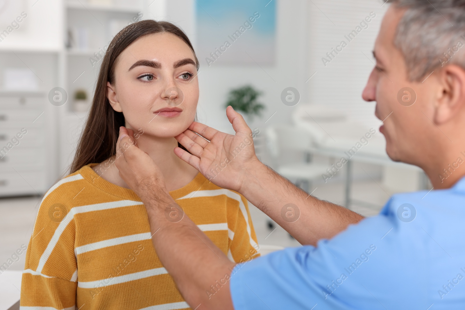 Photo of Doctor examining woman's throat in clinic during appointment