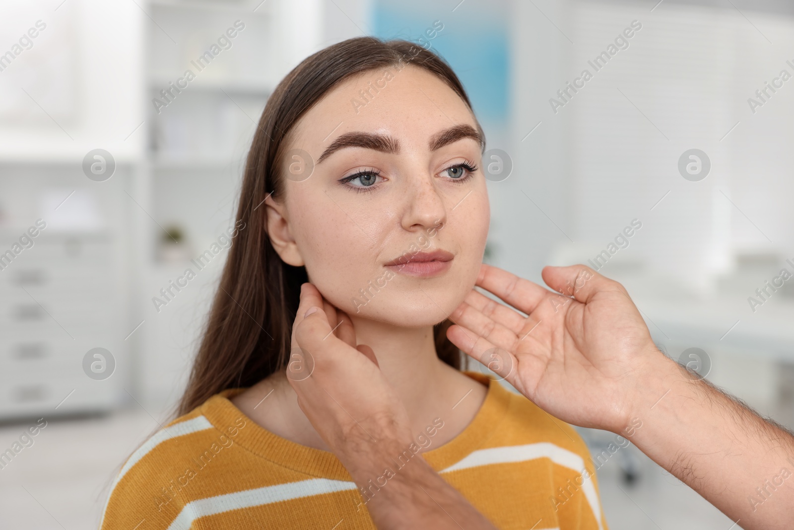 Photo of Doctor examining woman's throat in clinic during appointment