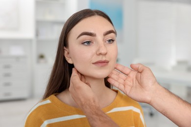 Photo of Doctor examining woman's throat in clinic during appointment