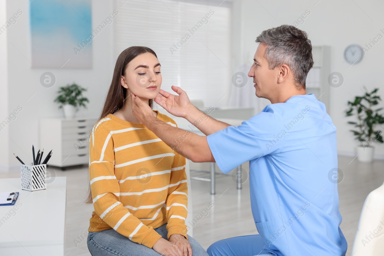 Photo of Doctor examining woman's throat in clinic during appointment