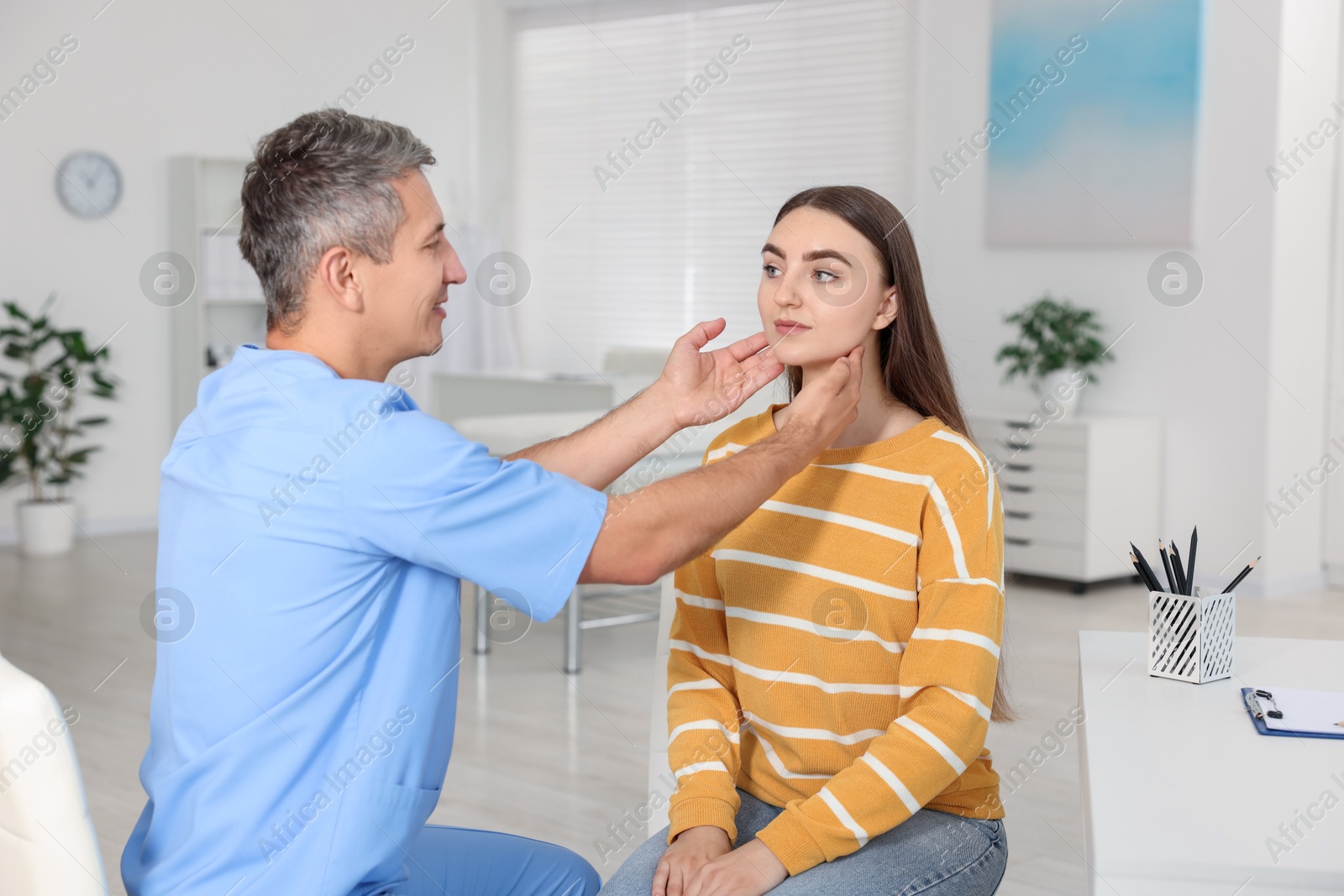 Photo of Doctor examining woman's throat in clinic during appointment