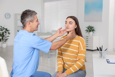 Photo of Doctor examining woman's throat in clinic during appointment