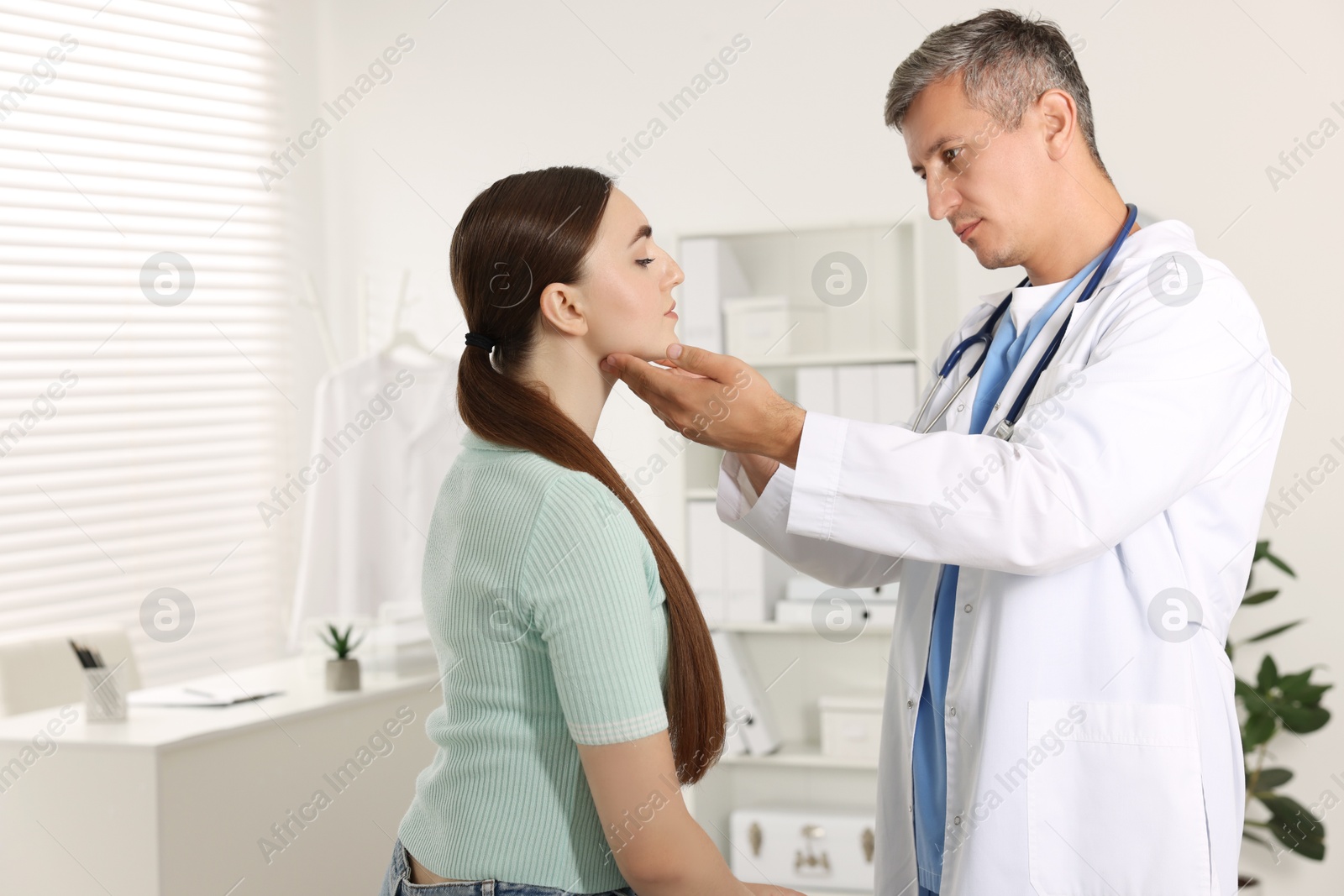 Photo of Doctor examining woman's throat in clinic during appointment