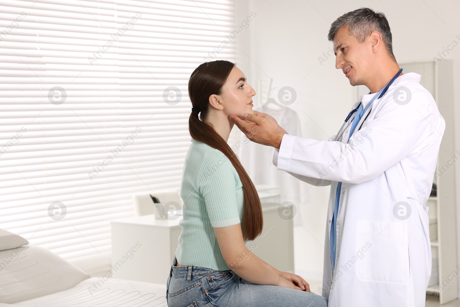 Photo of Doctor examining woman's throat in clinic during appointment