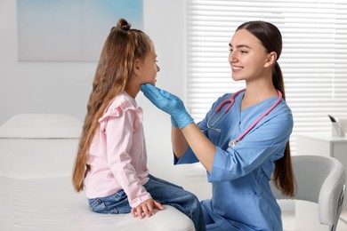 Photo of Doctor examining girl's throat in clinic during appointment