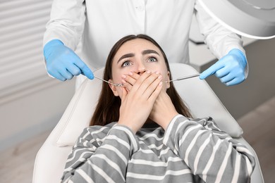 Dental phobia. Dentist working with scared woman in clinic, closeup