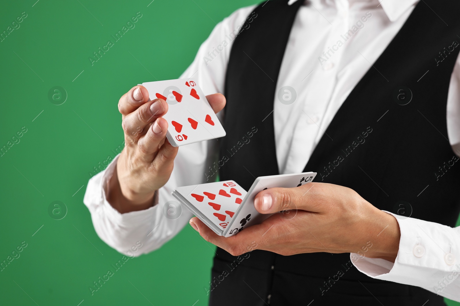 Photo of Professional croupier shuffling cards on green background, closeup