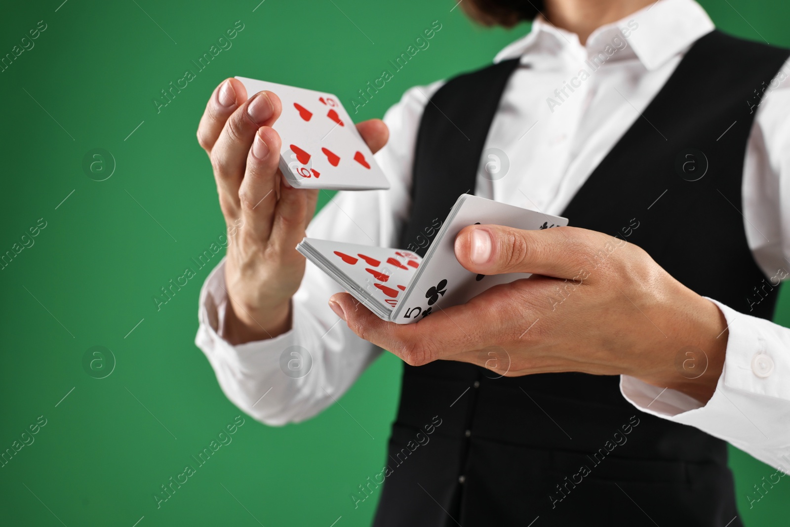 Photo of Professional croupier shuffling cards on green background, closeup