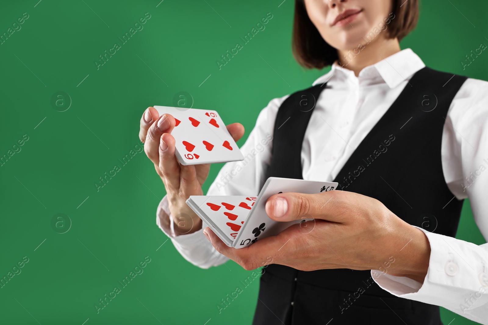 Photo of Professional croupier shuffling cards on green background, closeup