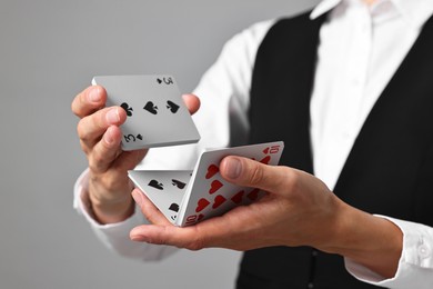 Photo of Professional croupier shuffling cards on grey background, closeup