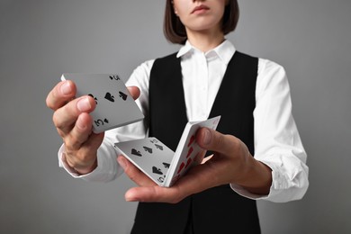 Professional croupier shuffling cards on grey background, closeup