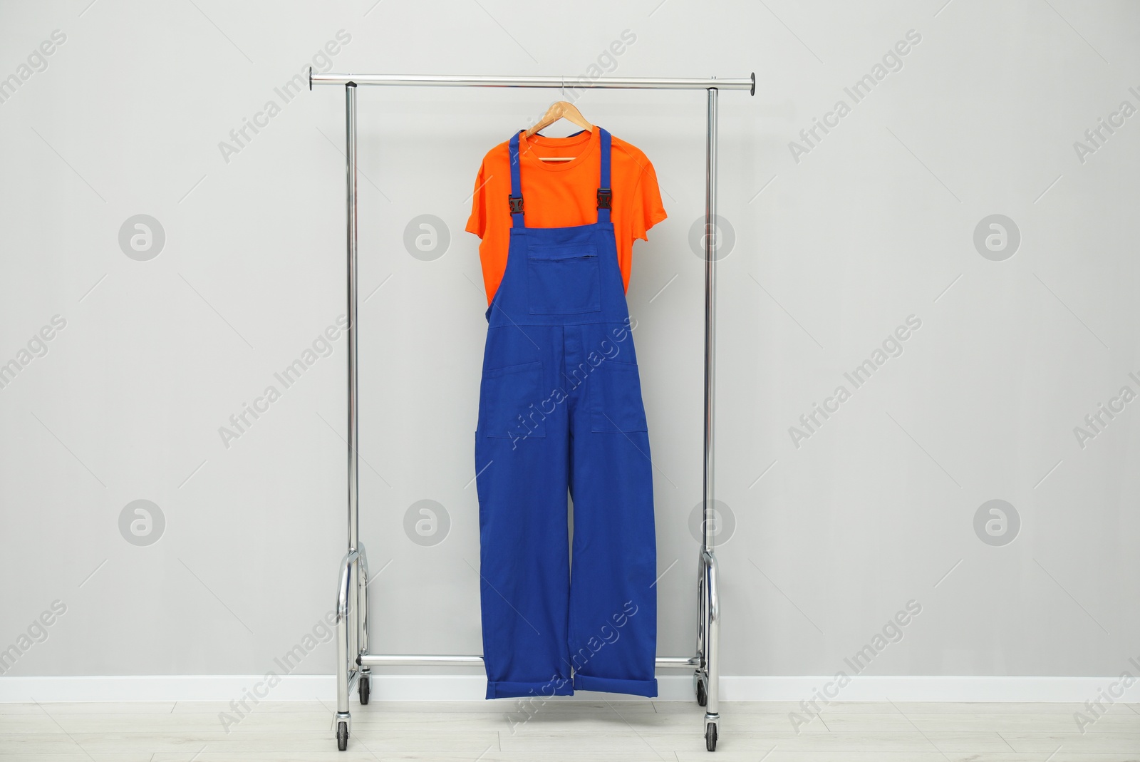 Photo of Worker's uniform on clothing rack near grey wall indoors