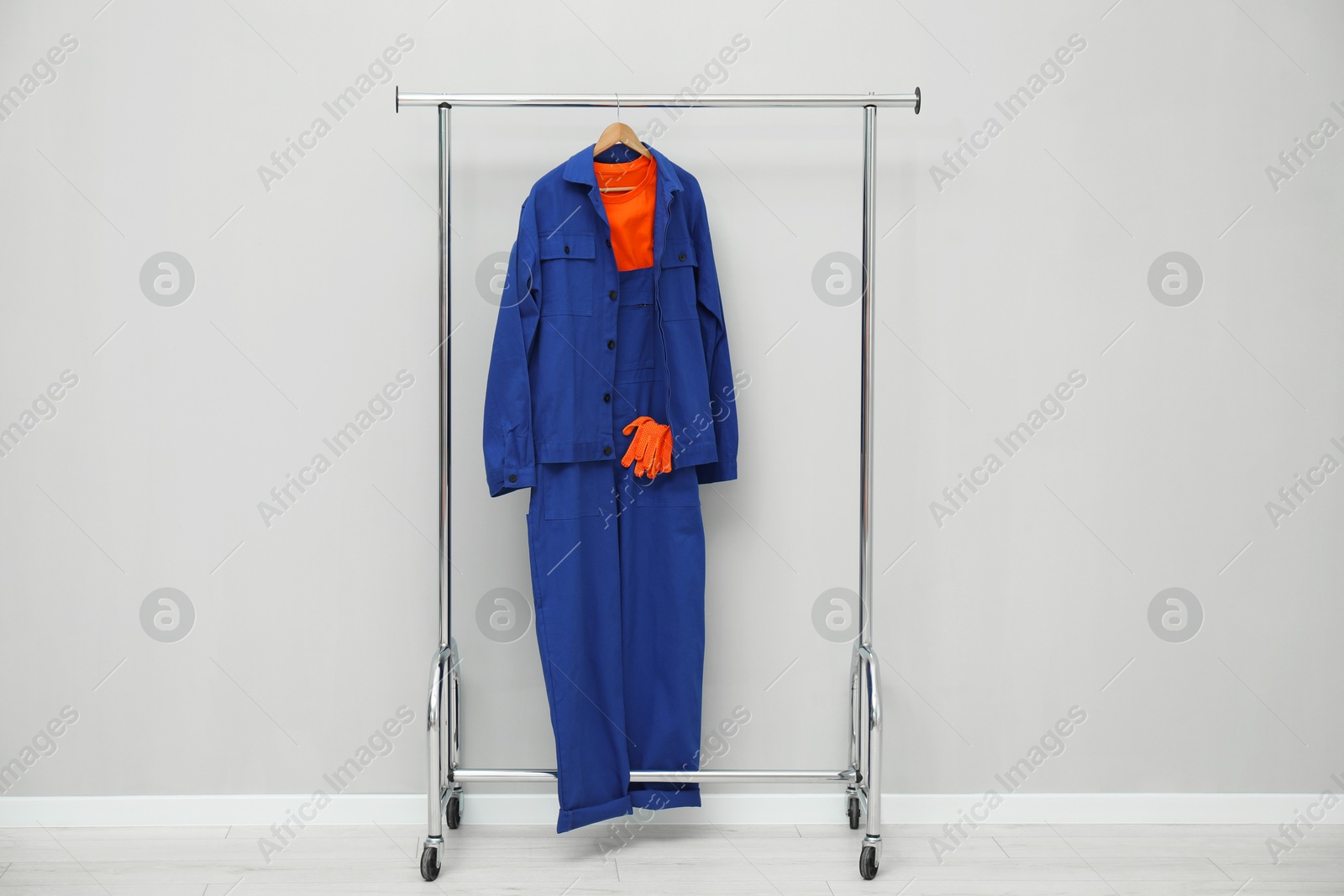 Photo of Worker's uniform on clothing rack near grey wall indoors