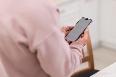 Man using modern smartphone indoors, closeup view