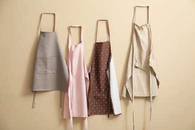 Photo of Many chef's aprons hanging on beige wall