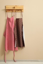 Photo of Two chef's aprons hanging on beige wall