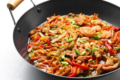 Photo of Stir-fry sea food in wok on light table, closeup