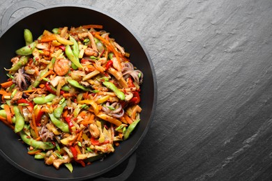 Photo of Stir-fry sea food in wok on grey textured table, top view. Space for text