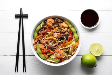 Photo of Stir-fry noodles with sea food served on white wooden table, flat lay