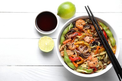 Photo of Stir-fry noodles with sea food served on white wooden table, flat lay