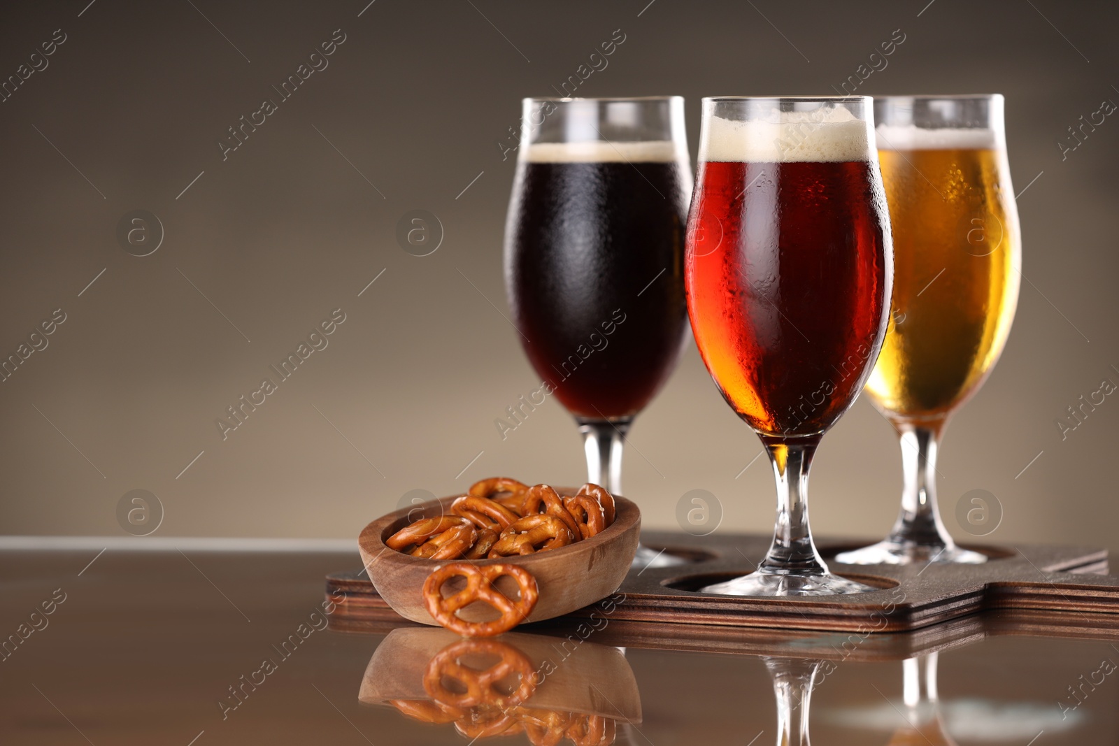 Photo of Glasses with different types of beer and snacks on mirror surface. Space for text