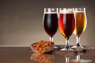 Photo of Glasses with different types of beer and snacks on mirror surface. Space for text