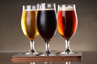 Photo of Glasses with different types of beer on mirror surface, closeup