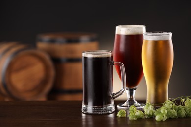 Photo of Glasses with different types of beer and fresh hops on wooden table in bar. Space for text