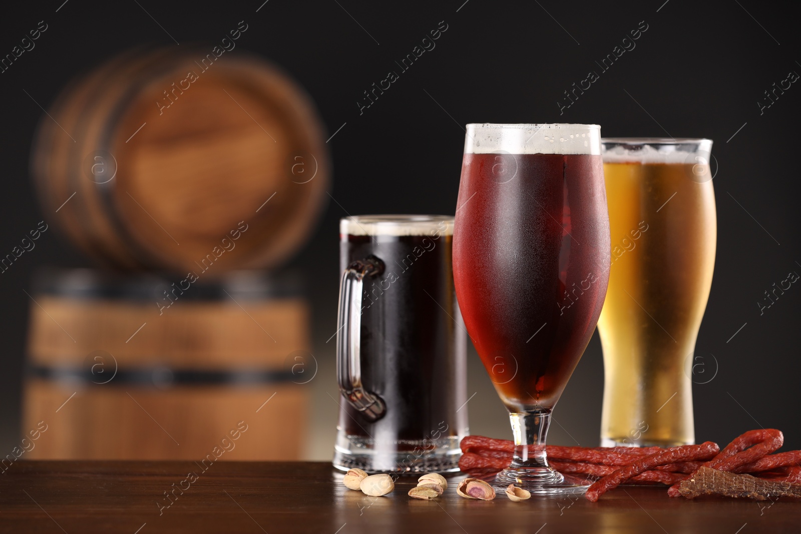 Photo of Glasses with different types of beer and snacks on wooden table in bar. Space for text