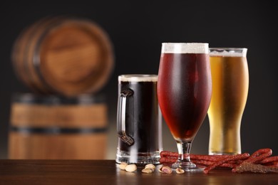 Photo of Glasses with different types of beer and snacks on wooden table in bar. Space for text