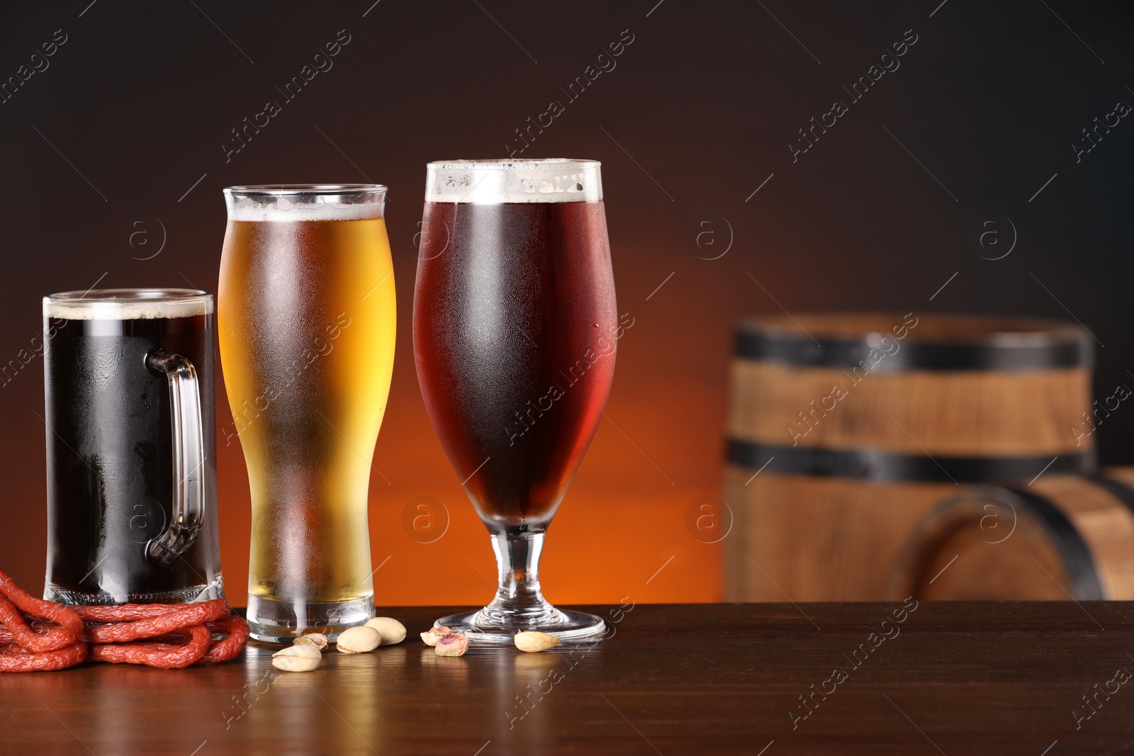 Photo of Glasses with different types of beer and snacks on wooden table in bar. Space for text