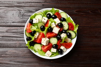 Photo of Delicious salad with feta cheese on wooden table, top view