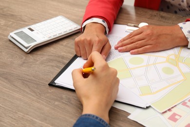 Photo of Real estate agent working with client at wooden table, closeup