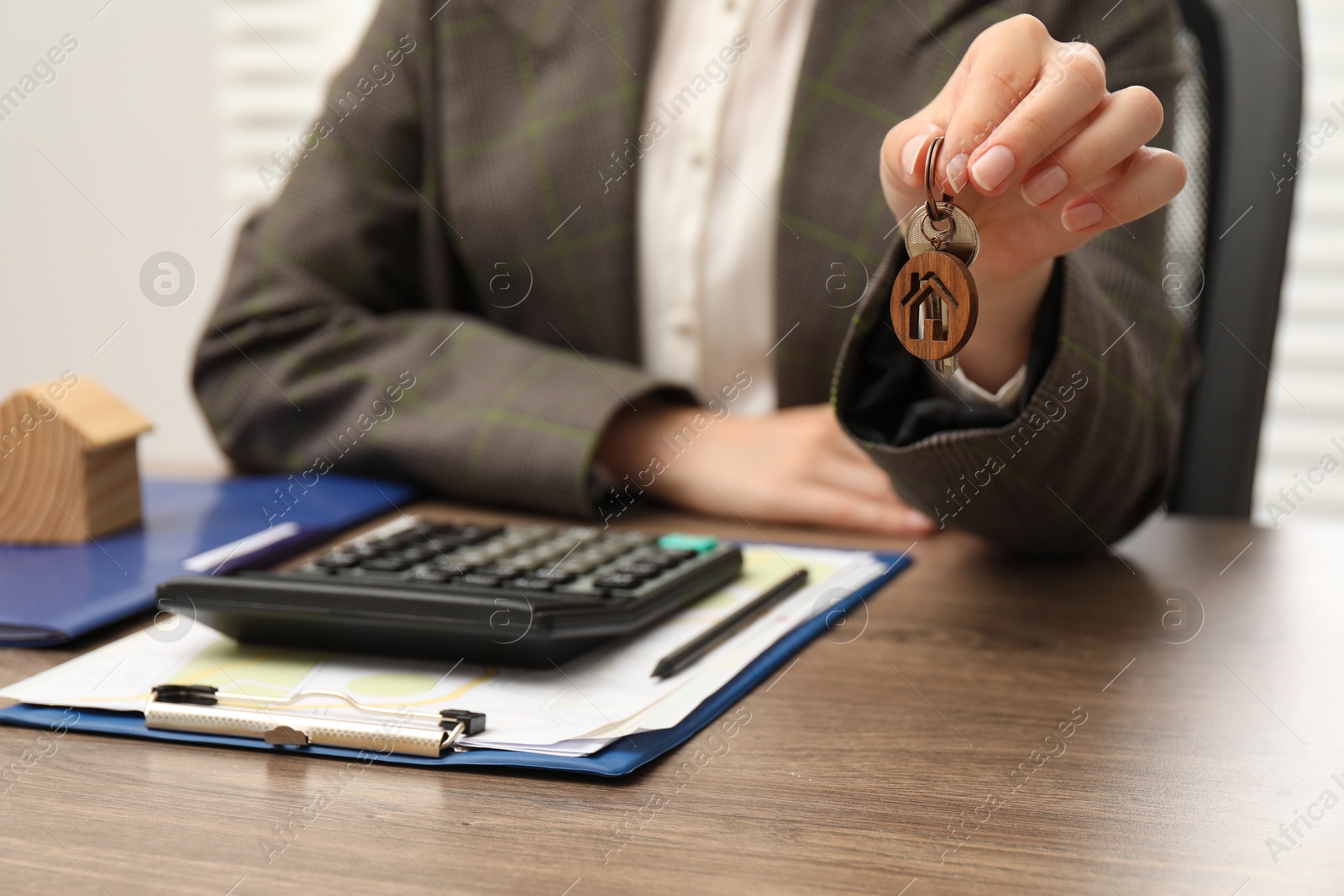 Photo of Real estate agent with house key and stationery at wooden table, closeup