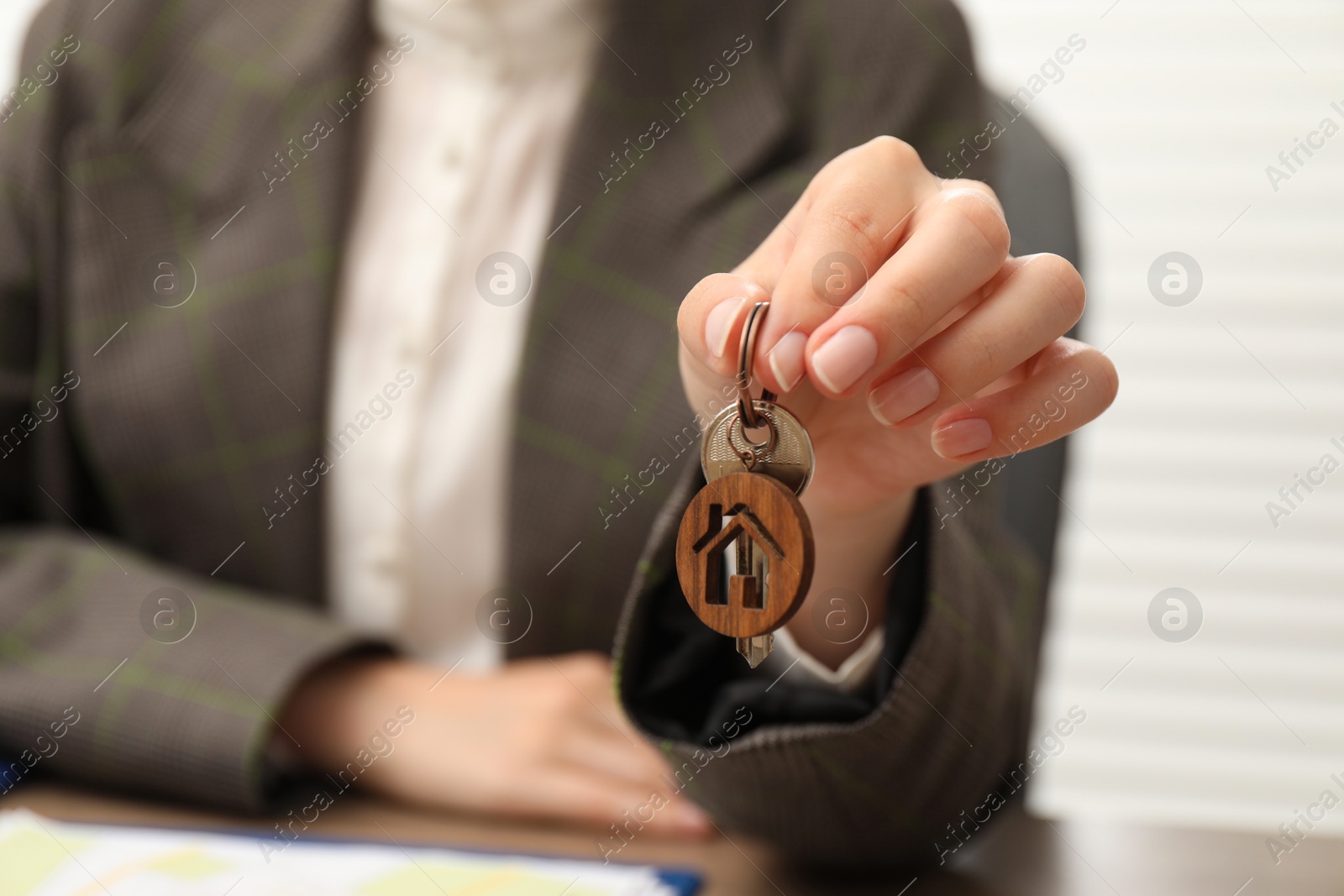 Photo of Real estate agent with house key at table, closeup