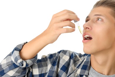 Photo of Young man taking CBD tincture indoors. Herbal extract