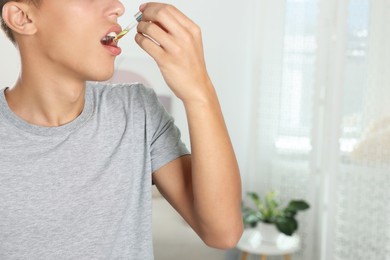 Photo of Young man taking CBD tincture indoors, closeup. Space for text