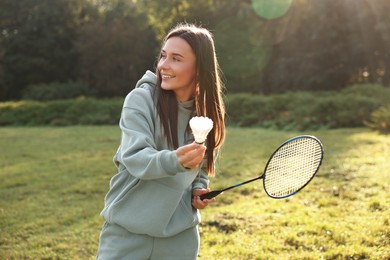 Photo of Happy young woman playing badminton racket in park on sunny day