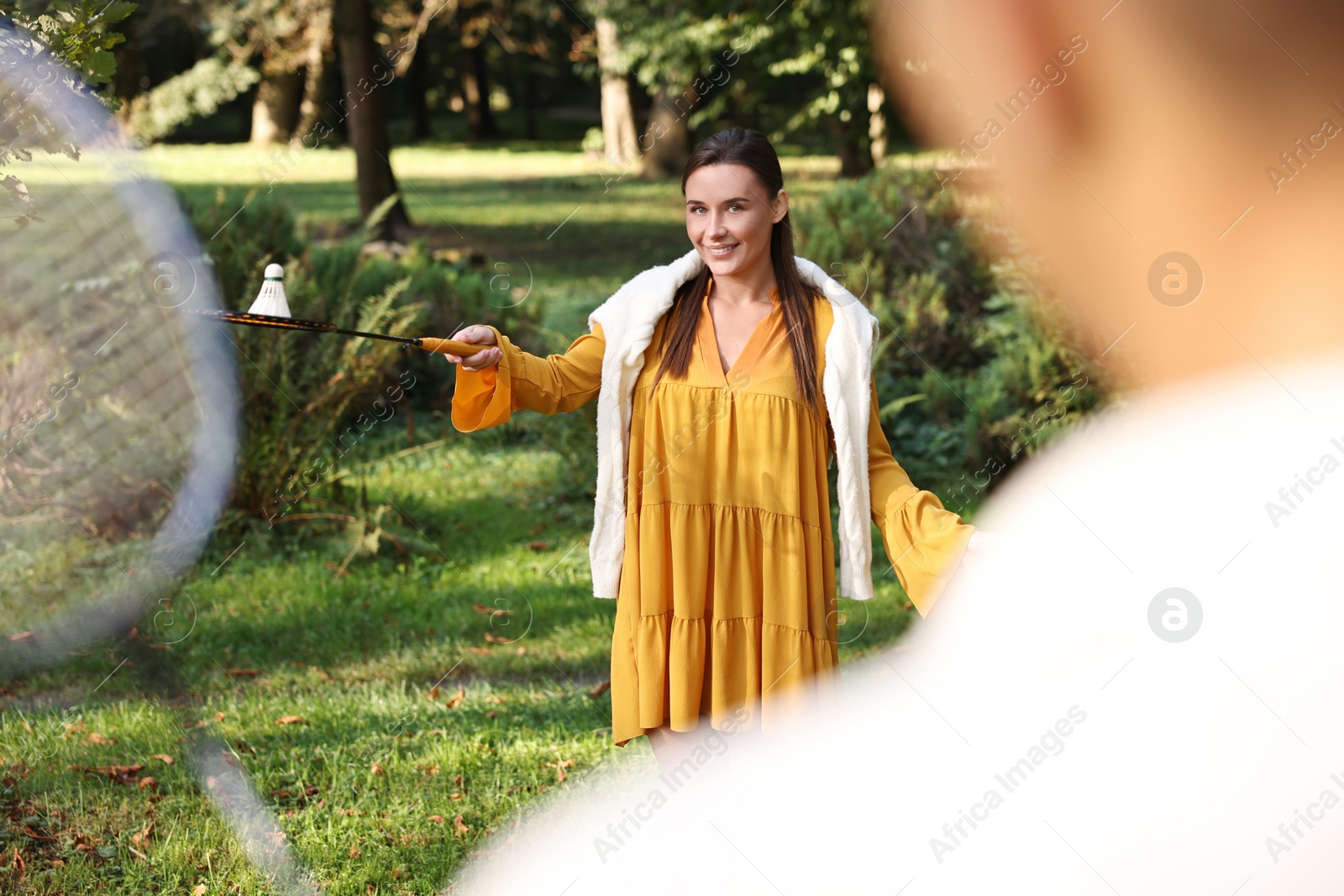 Photo of Young woman and man playing badminton in park, selective focus