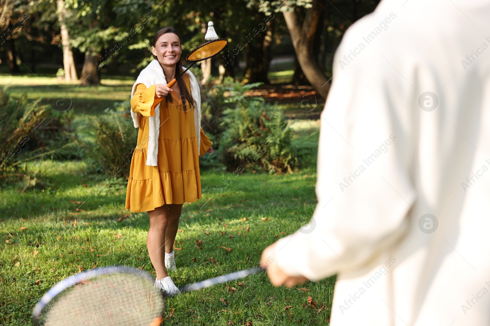 Photo of Young woman and man playing badminton in park, selective focus