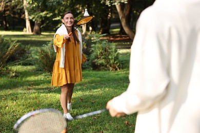 Photo of Young woman and man playing badminton in park, selective focus