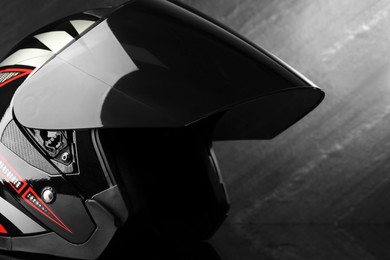 Photo of Modern motorcycle helmet with visor on dark gray background, closeup