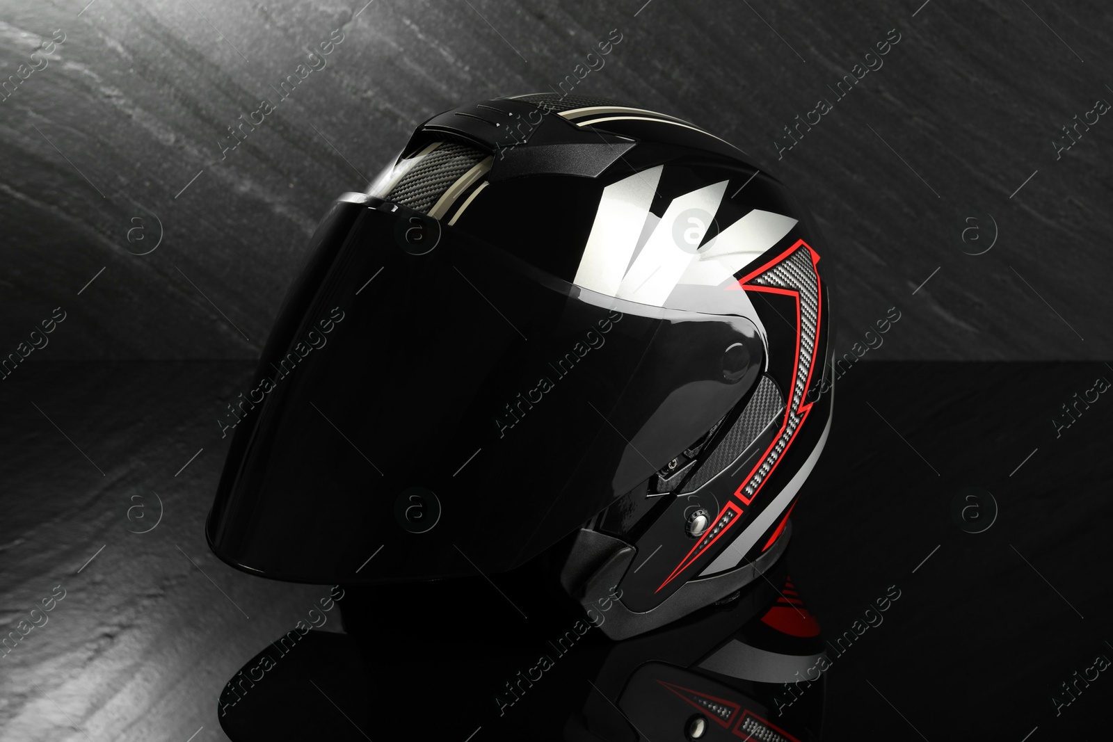 Photo of Modern motorcycle helmet with visor on dark gray background