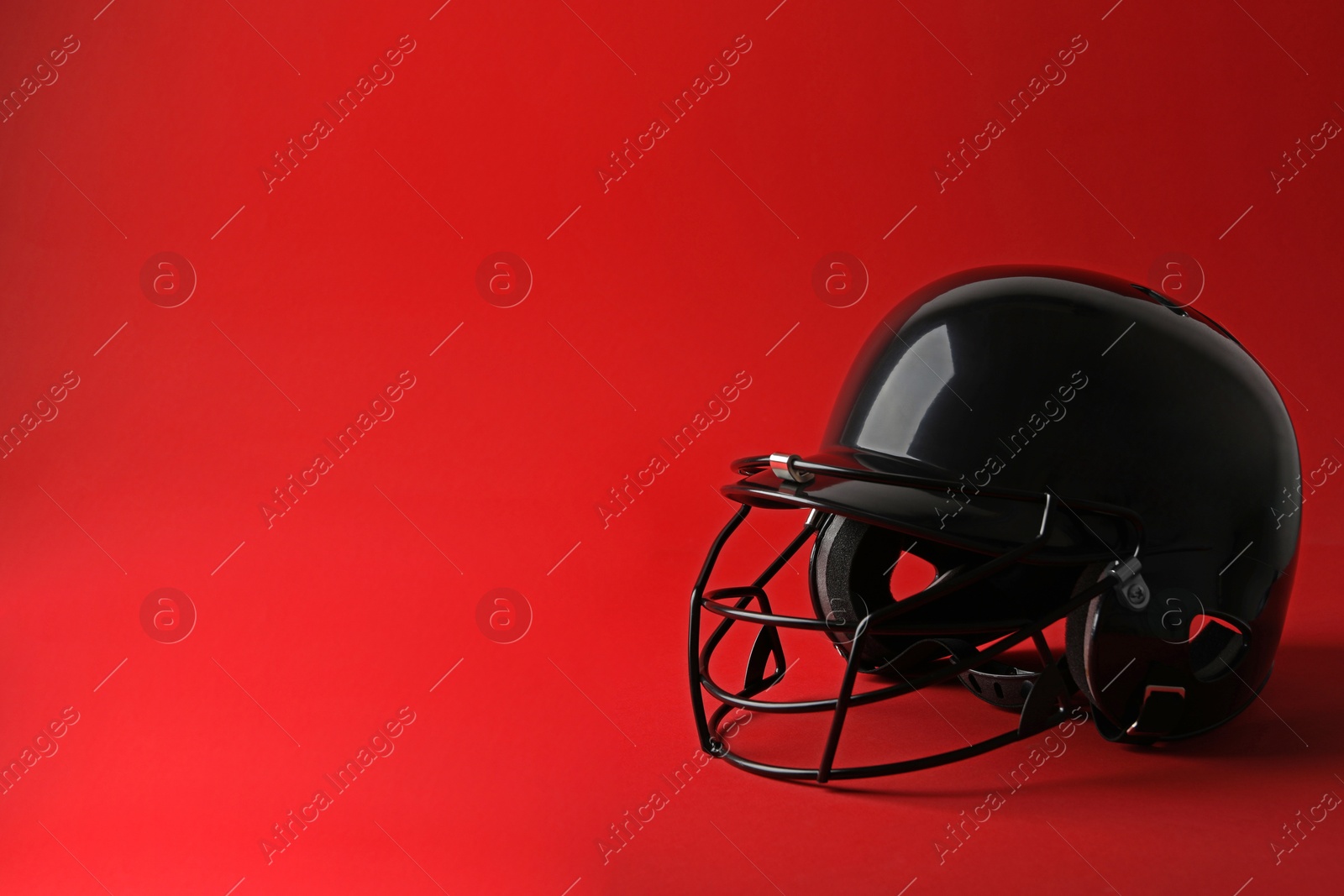 Photo of Black baseball helmet on red background, space for text