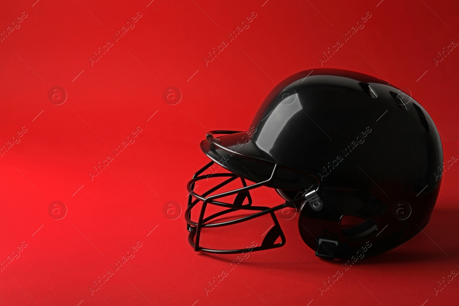 Photo of Black baseball helmet on red background, space for text