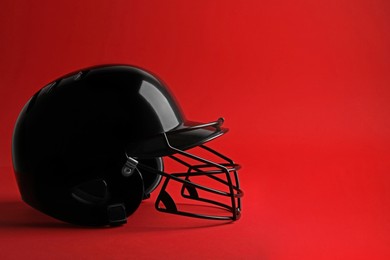 Photo of Black baseball helmet on red background, space for text