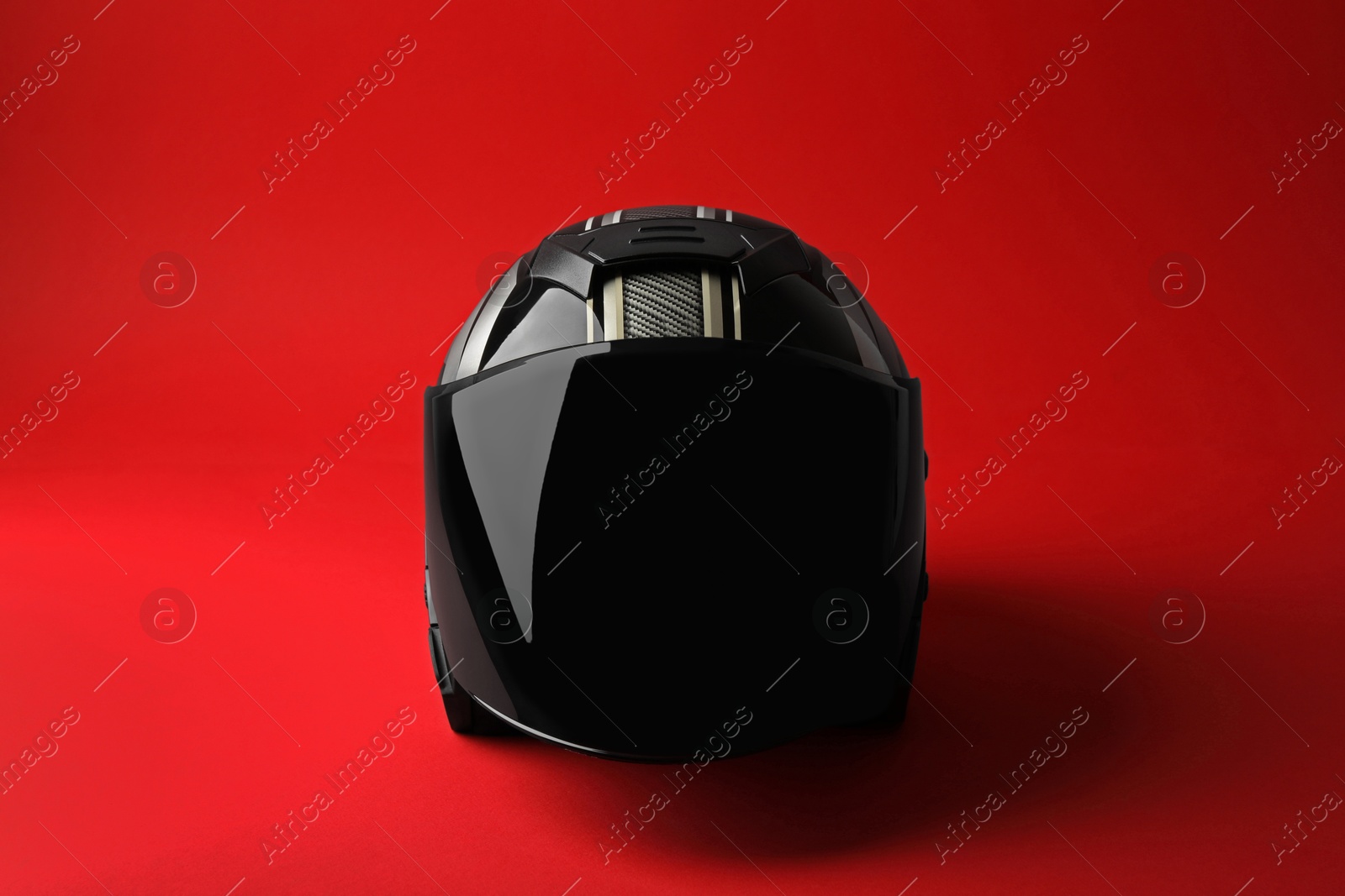 Photo of Modern motorcycle helmet with visor on red background